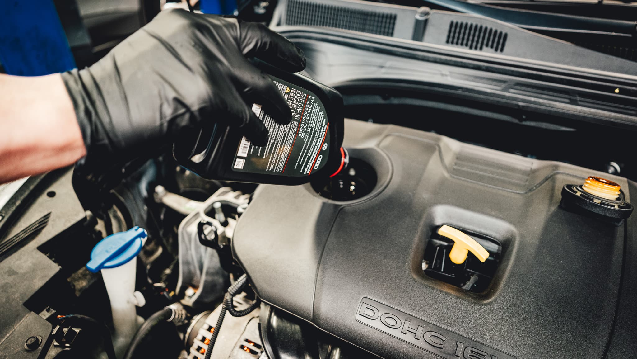 Technician pouring engine oil during an oil change service.