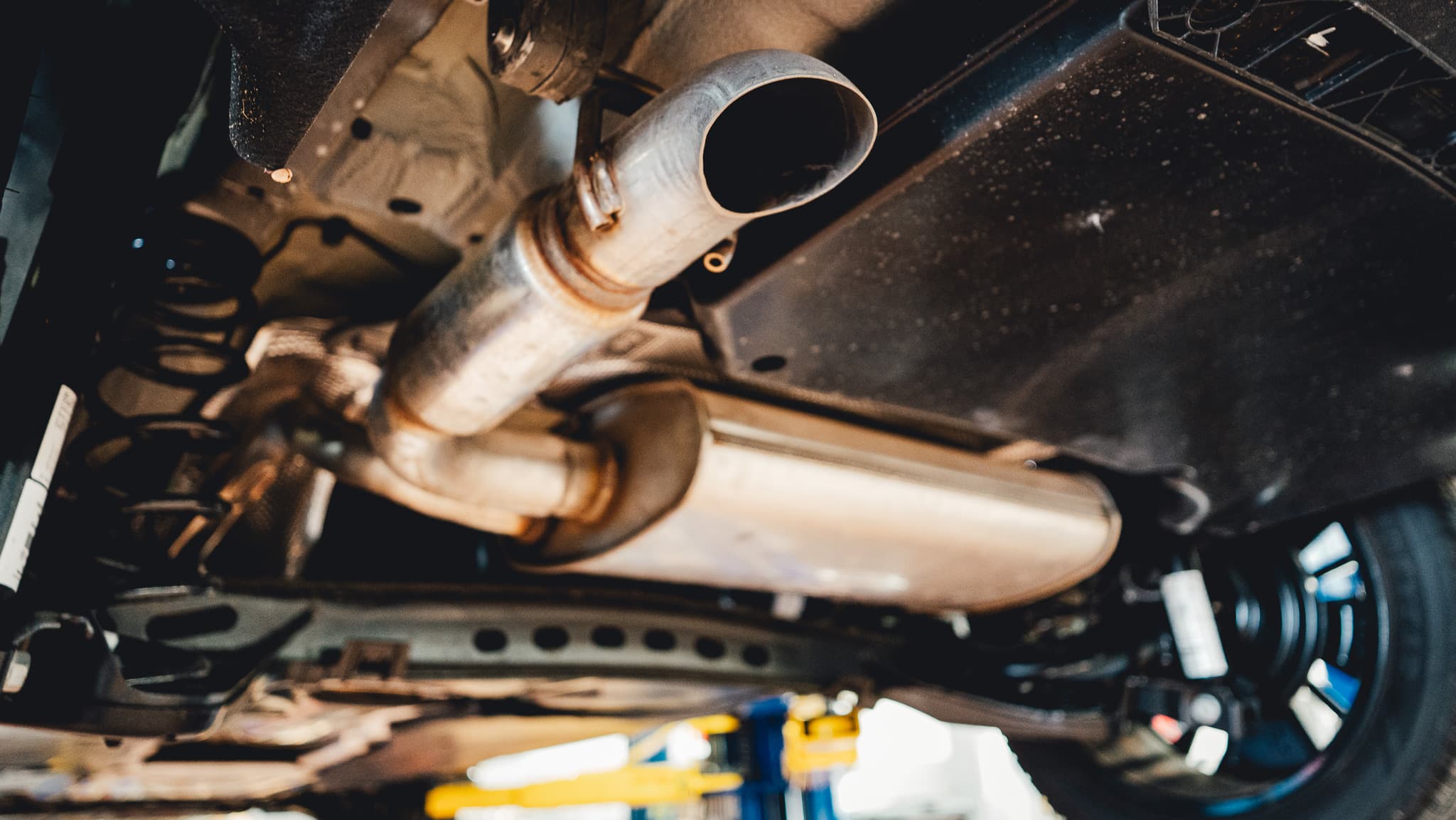 Detailed undercar exhaust and emissions system view inside the shop.